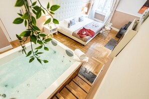 Un dormitorio moderno con una cama grande, una mesita de noche, una ventana con cortinas y una bañera con toalla.