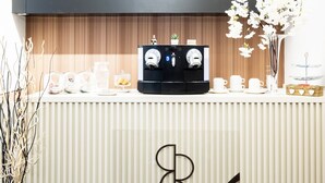 Uma área de recepção com um espaço para café, um vaso com flores brancas e o logotipo do Rome River Inn.
