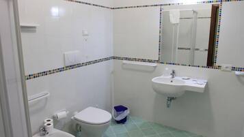 Une salle de bain avec des toilettes, un lavabo et un miroir.