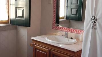 Casa de banho com lavatório branco, toucador de madeira e espelho com moldura decorativa.