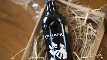 A bottle of Charisma wine in a wooden crate with straw, accompanied by three wine glasses.