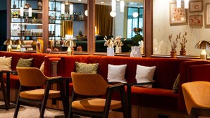 A cozy bar area with red seating, wooden chairs, and a bar counter with bottles and glasses.