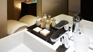 A modern bathroom with a bathtub, a mirror, and toiletries on the sink. - Hotel Mercure Villefranche-sur-Saone (Villefranche-sur-Saône)