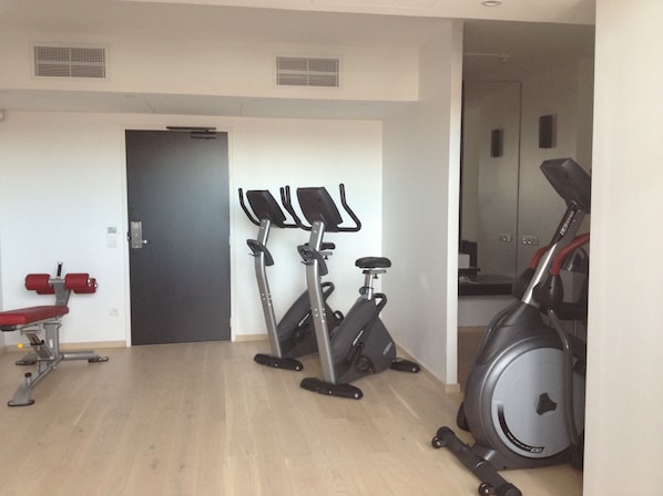 A gym with exercise equipment including a treadmill, stationary bikes, and a rowing machine. - Hotel Mercure Villefranche-sur-Saone (Villefranche-sur-Saône)