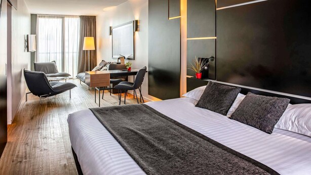 A modern hotel room with a large bed, a desk, and a seating area. - Hotel Mercure Villefranche-sur-Saone (Villefranche-sur-Saône)