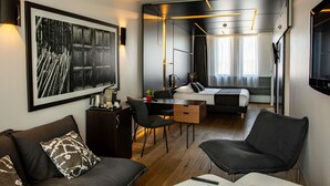 A modern hotel room with a large bed, a desk, a sofa, and a dining area. - Hotel Mercure Villefranche-sur-Saone (Villefranche-sur-Saône)