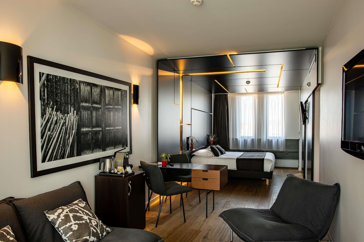Une chambre d’hôtel moderne équipée d’un grand lit, d’un bureau, d’un canapé et d’un coin repas.