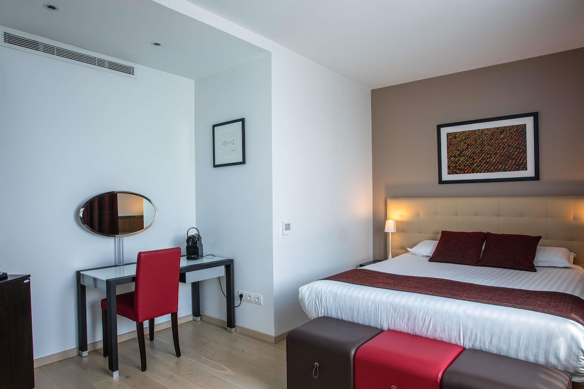 Une chambre d’hôtel équipée d’un lit, d’un bureau, d’une chaise, d’un miroir et d’un tableau accroché au mur.