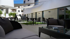 An outdoor seating area with modern furniture, including sofas and tables, under a shaded canopy. - Hotel Mercure Villefranche-sur-Saone (Villefranche-sur-Saône)