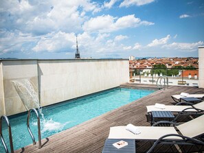 A rooftop pool with a wooden deck, lounge chairs, and a view of a cityscape. - Hotel Mercure Villefranche-sur-Saone (Villefranche-sur-Saône)