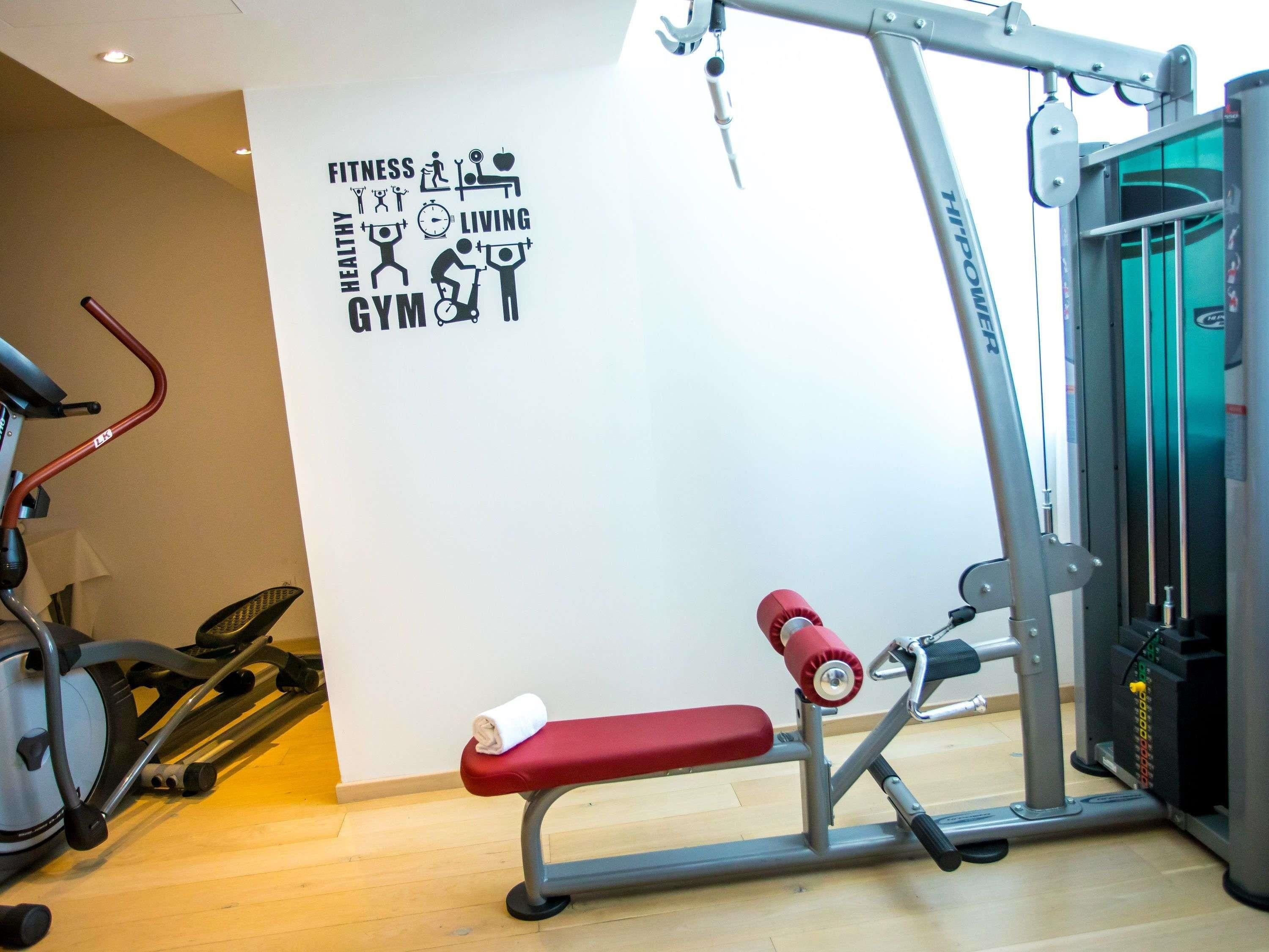 Un gimnasio con equipo de ejercicio, una pared con palabras relacionadas con el fitness y un banco.