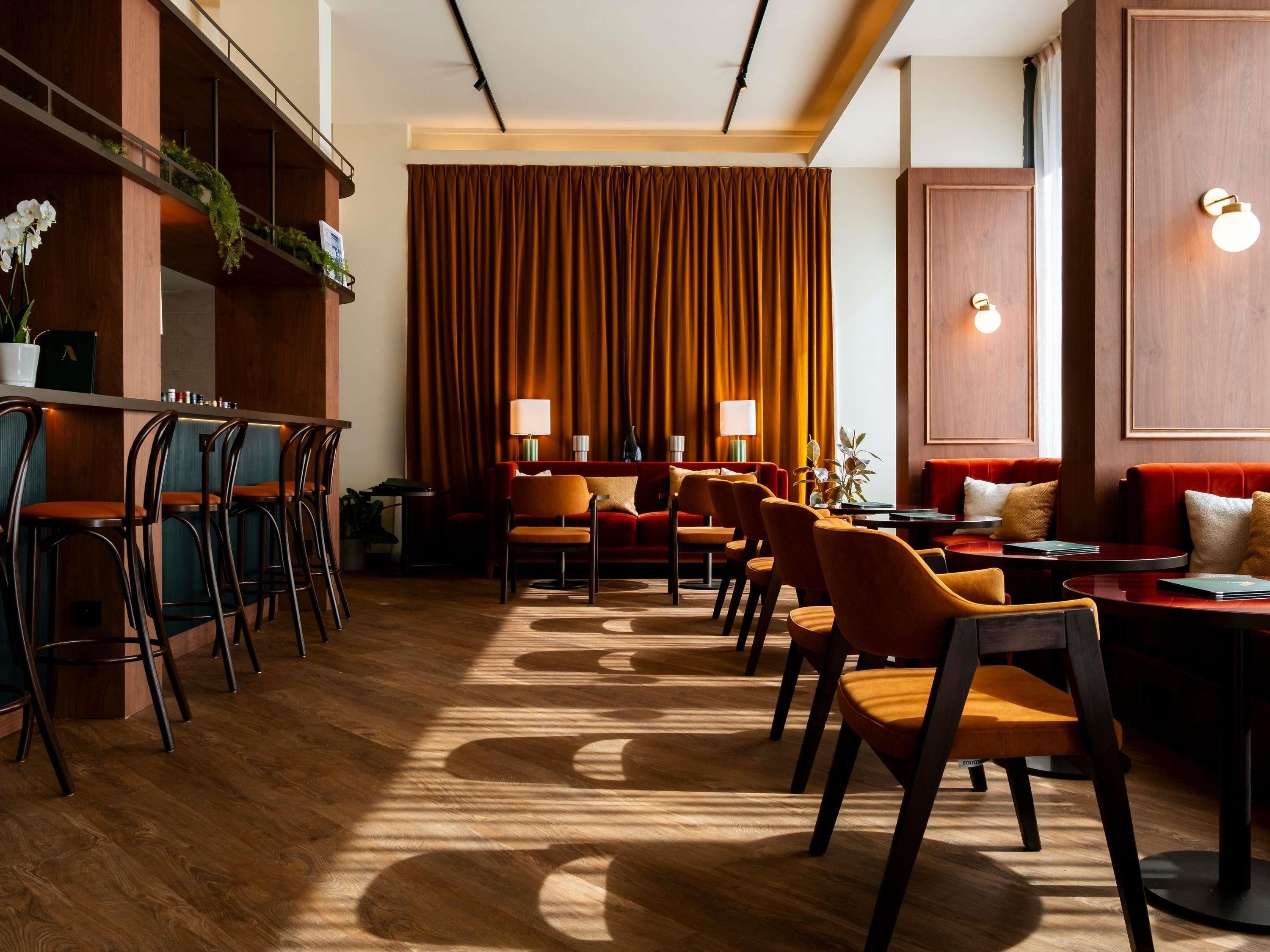 A restaurant with wooden floors, red upholstered seating, and a bar area with stools.