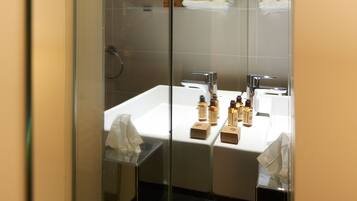 Un baño moderno con dos lavamanos, cabina de ducha de vidrio y un espejo.