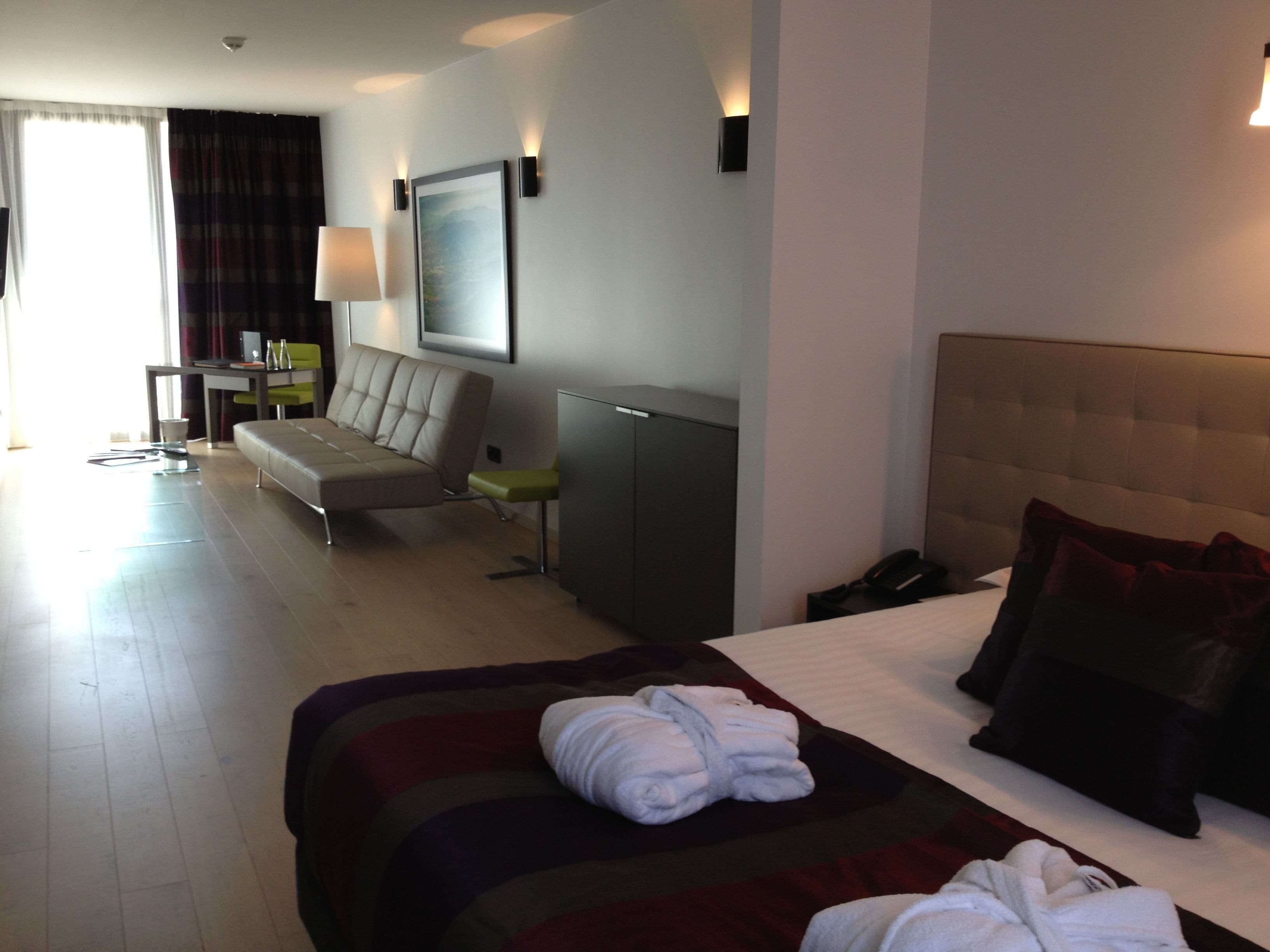 A hotel room with a bed, a sofa, a desk, and a chair.