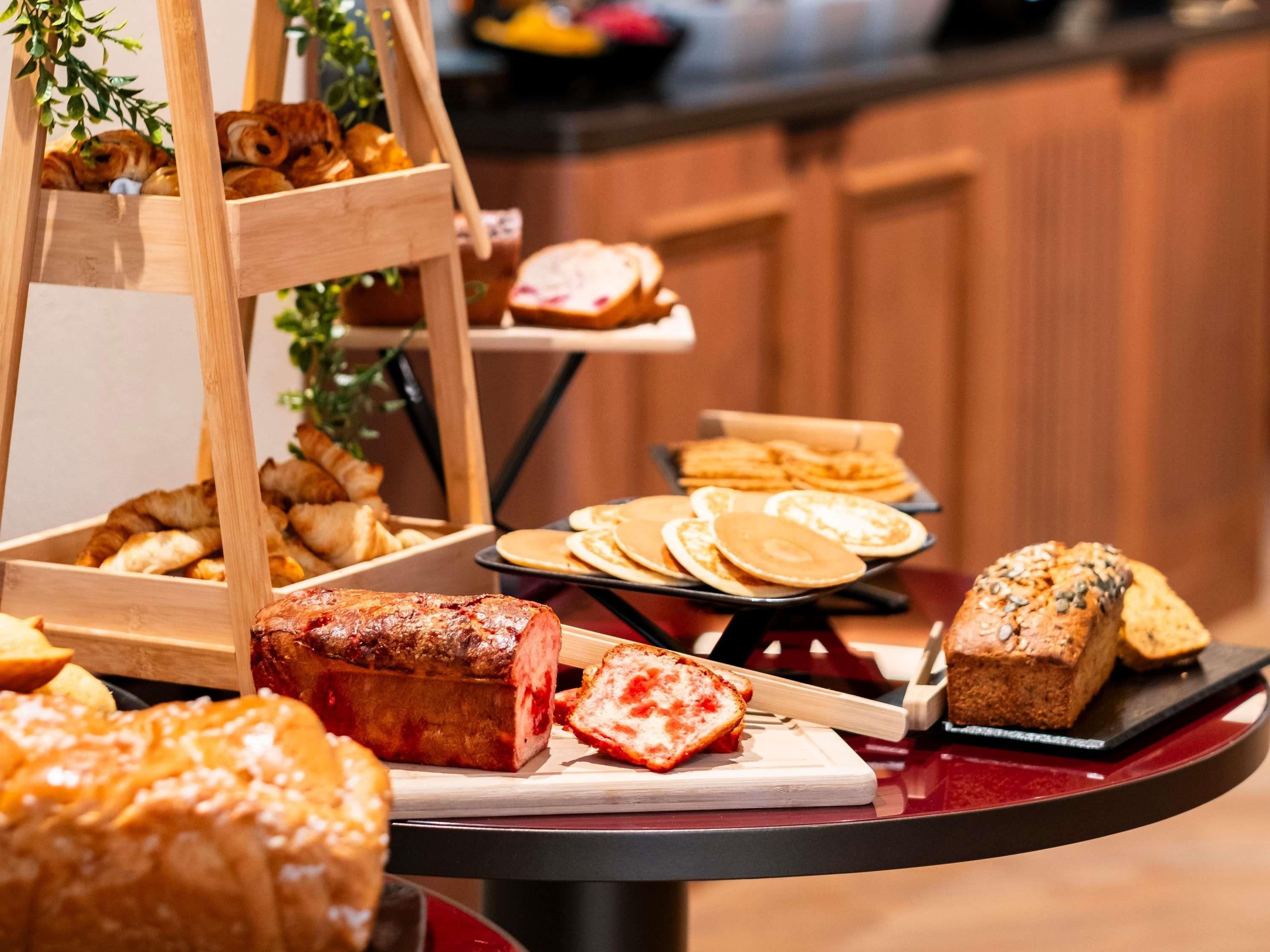 A buffet table with various food items including pastries, bread, and a loaf of bread.