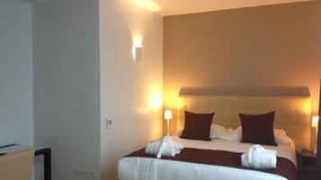 A hotel room with a large bed, two bedside lamps, and a headboard with a light panel.