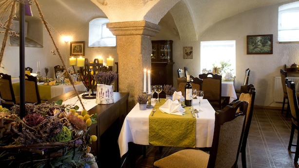 A restaurant with tables set for dining, featuring a rustic interior with stone pillars and a chandelier. - L' Auberge Gutshof (Bischofswerda)