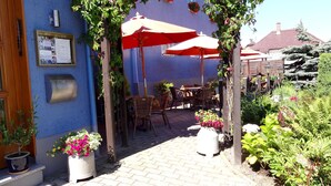 A courtyard with outdoor seating, potted plants, and a blue wall. - L' Auberge Gutshof (Bischofswerda)