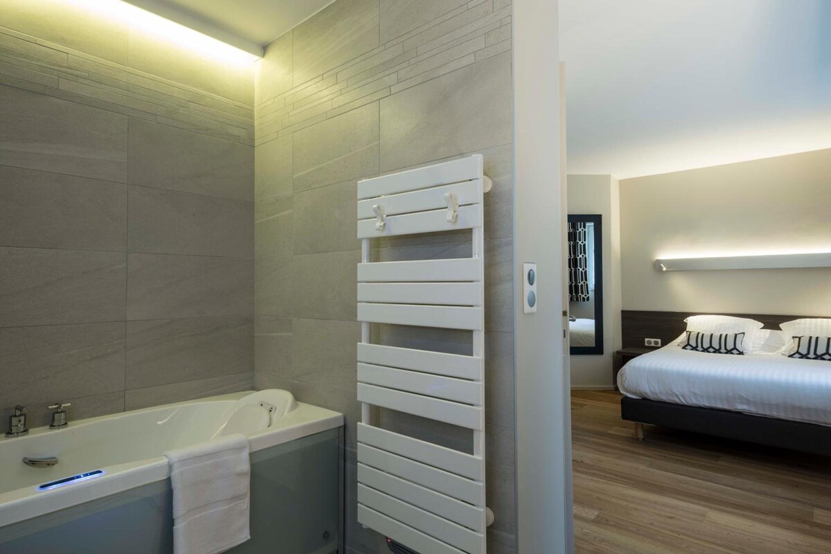 A modern bathroom with a bathtub, a towel rack, and a shower area.