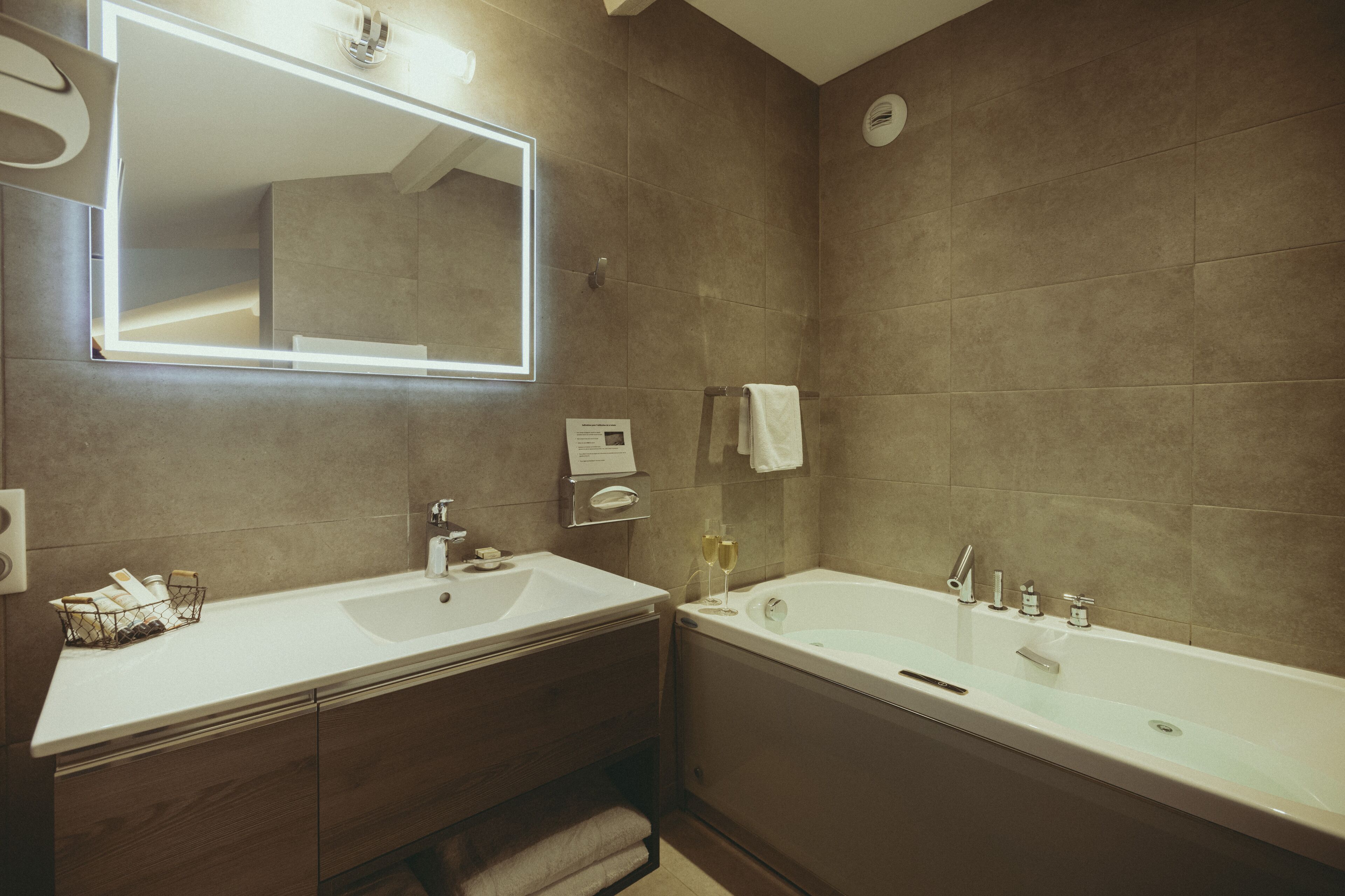 A modern bathroom with a large mirror, two sinks, and a bathtub.