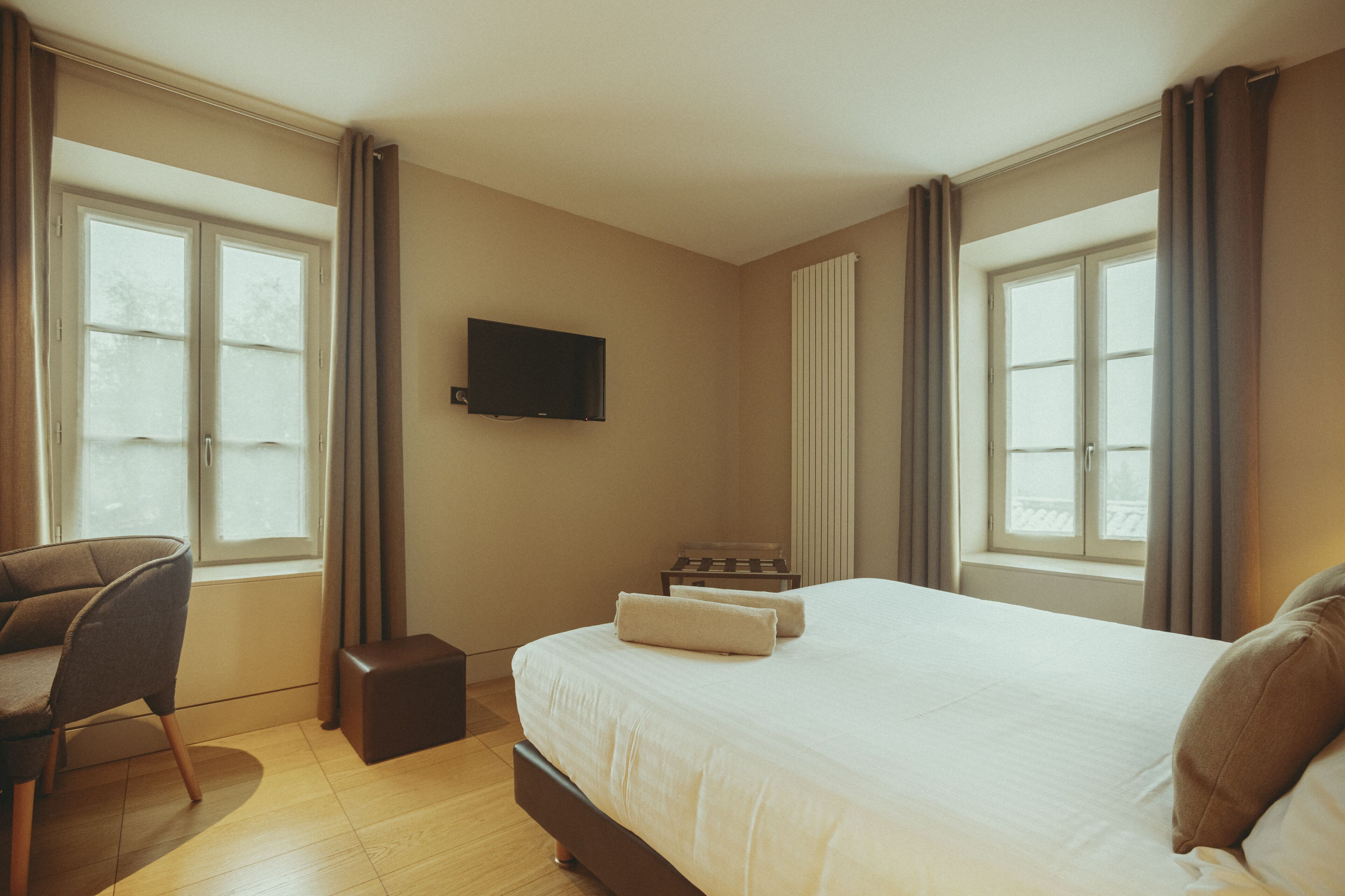 A hotel room with a large bed, a TV mounted on the wall, and a desk with a chair.