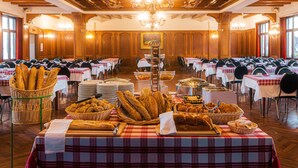 A banquet hall with tables set for a meal, featuring a variety of breads and pastries.