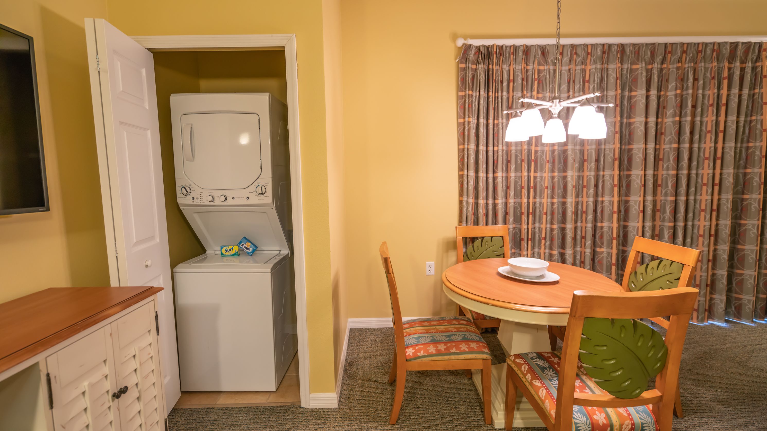 A compact living space with a dining area, a washing machine, and a small kitchen area.