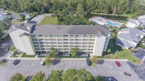 A multi-story hotel with a central courtyard, parking lot, and a swimming pool. - Barefoot Suites (Kissimmee)