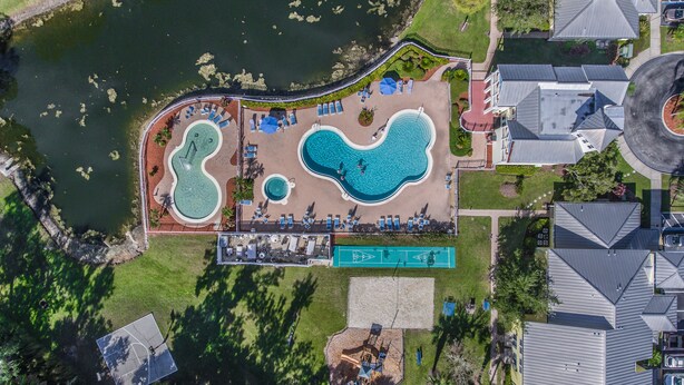 Eine Luftaufnahme eines Resorts mit zwei großen Schwimmbecken, einem Tennisplatz und einem kleinen Spielplatz.