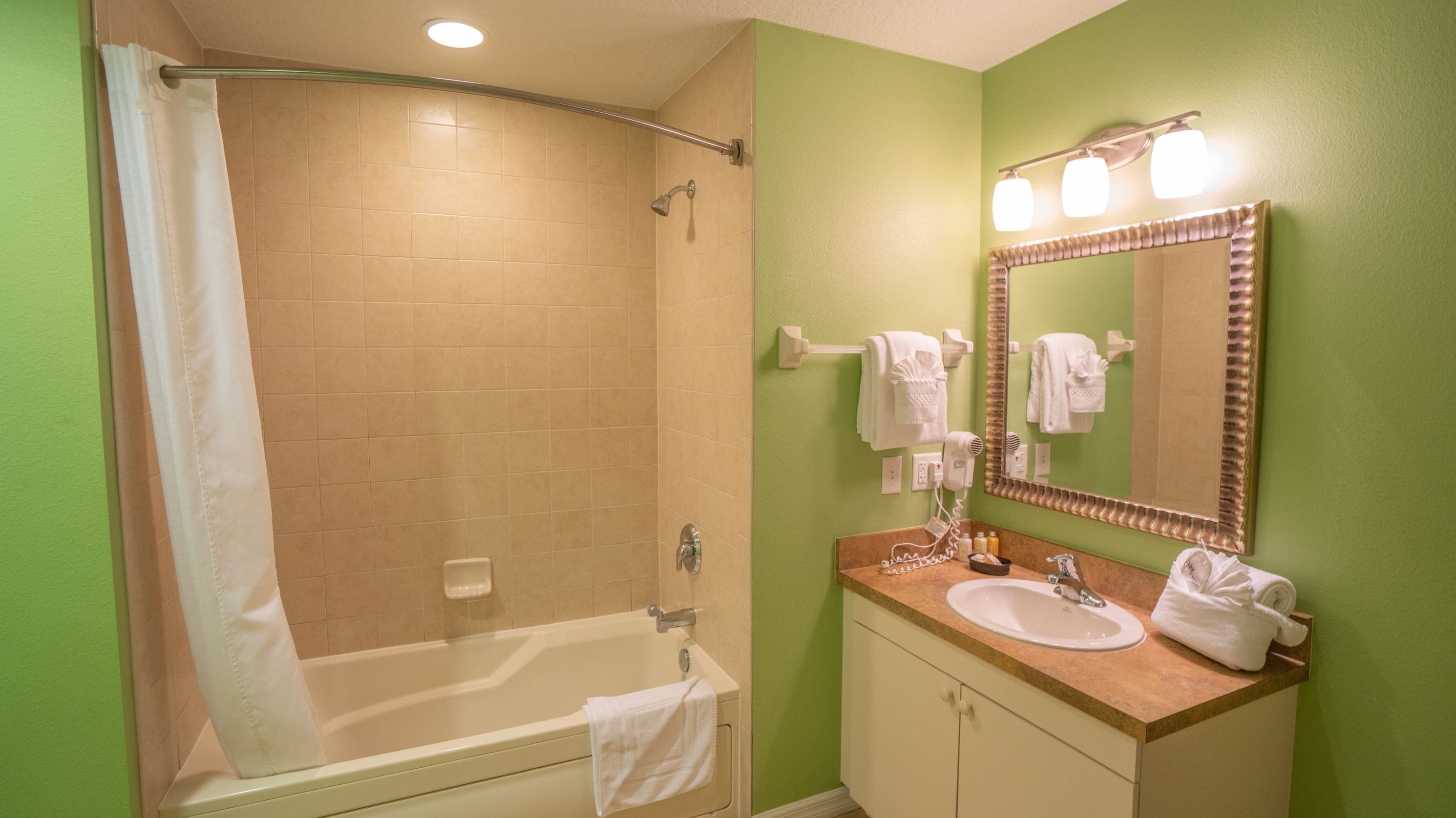 Une salle de bain équipée d’une baignoire, d’un lavabo, d’un miroir et d’un rideau de douche.