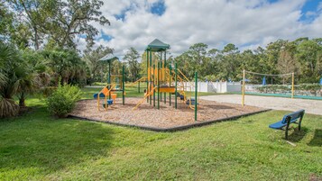 A playground with a climbing structure, slides, and a covered area.