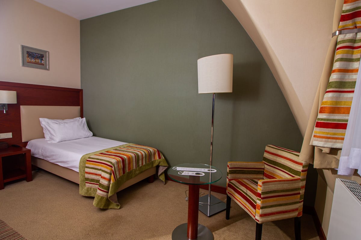 Habitación de hotel con una cama, una silla, una mesa y una lámpara.