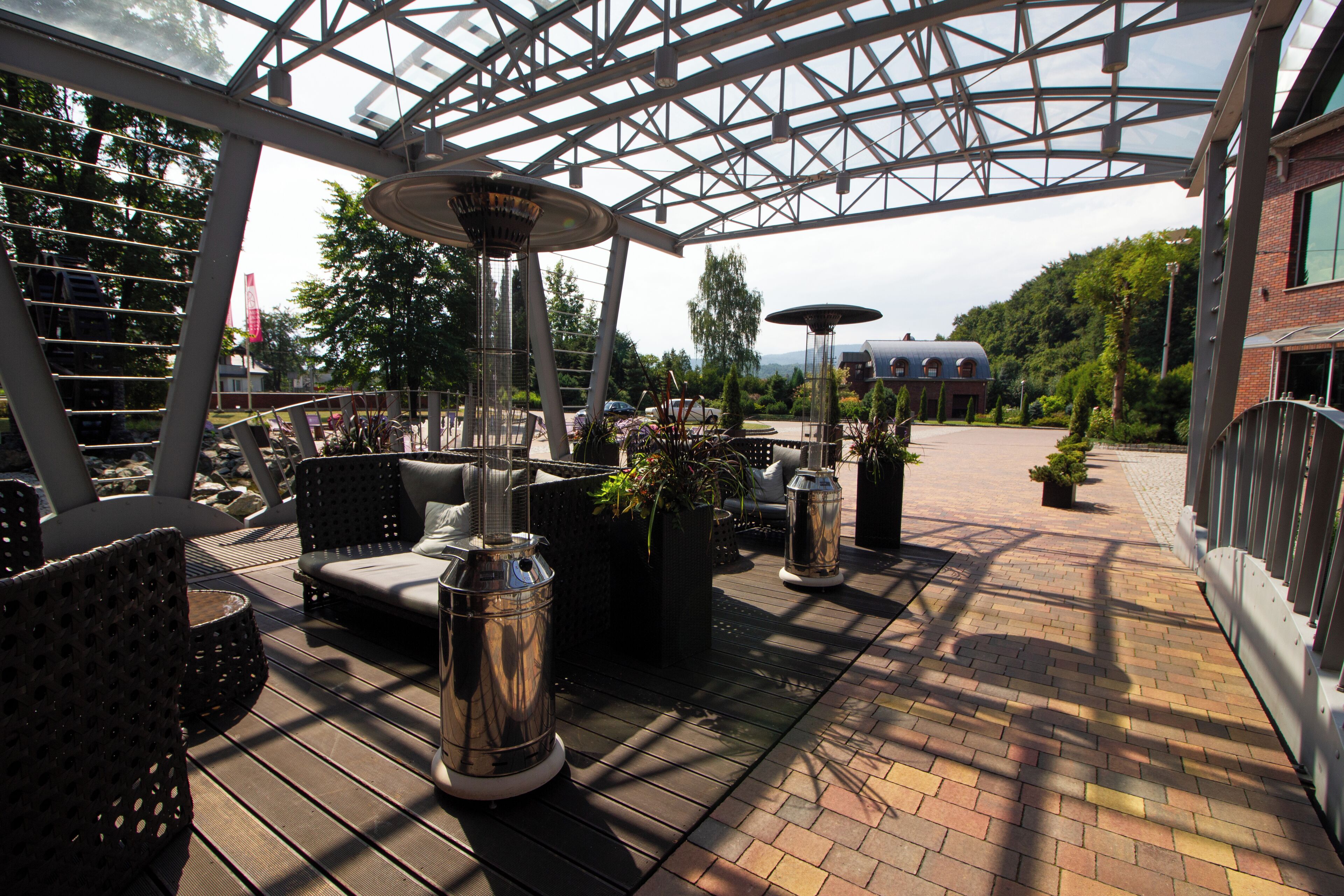 An outdoor patio with seating, planters, and a glass ceiling structure.