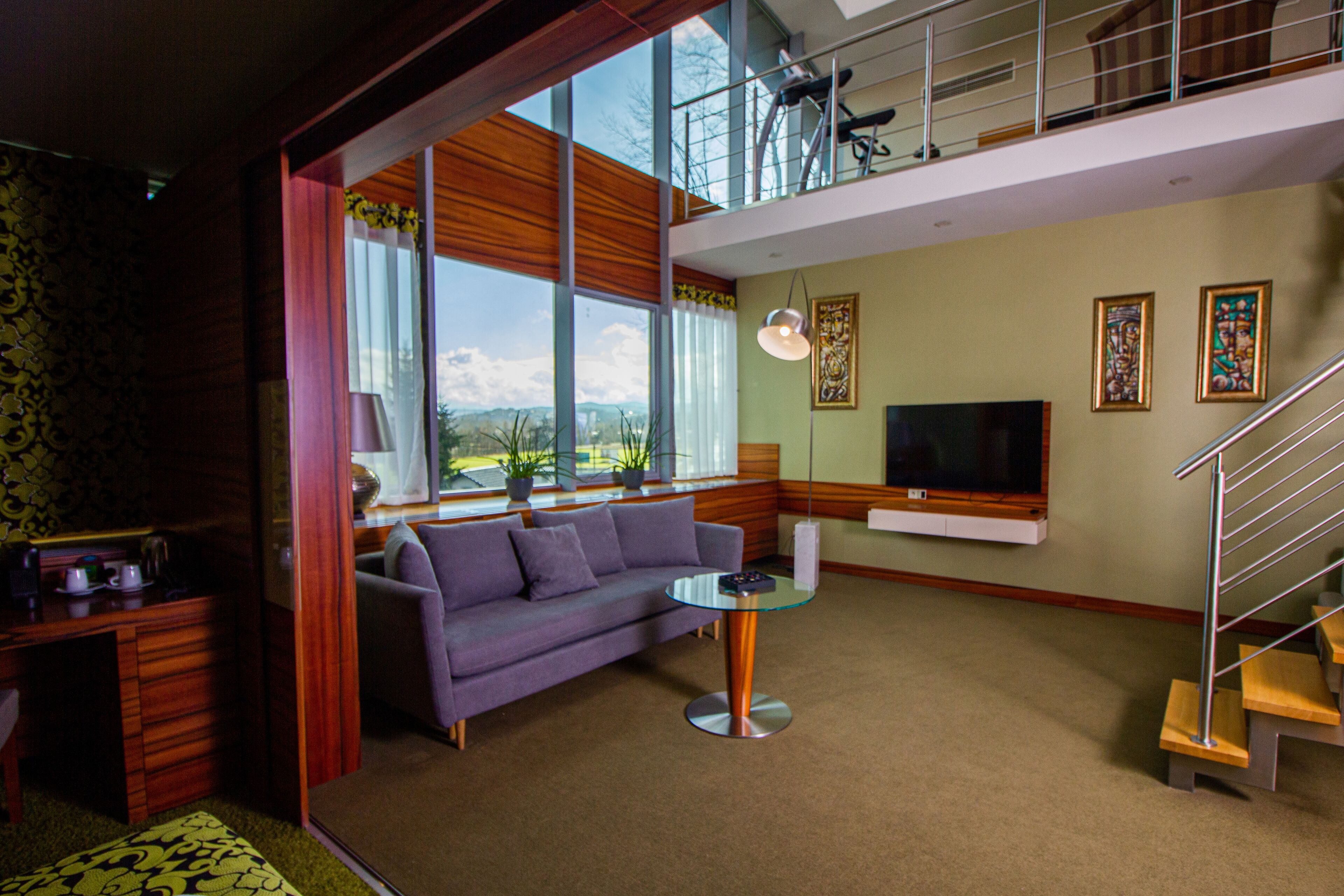Una sala de estar moderna con un sofá, una mesa de centro de vidrio, un televisor y una escalera.