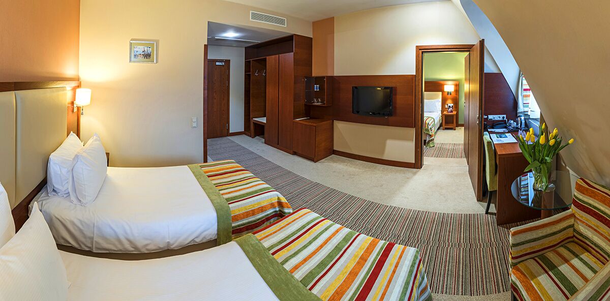 A hotel room with a bed, a desk, a TV, and a walk-in closet.