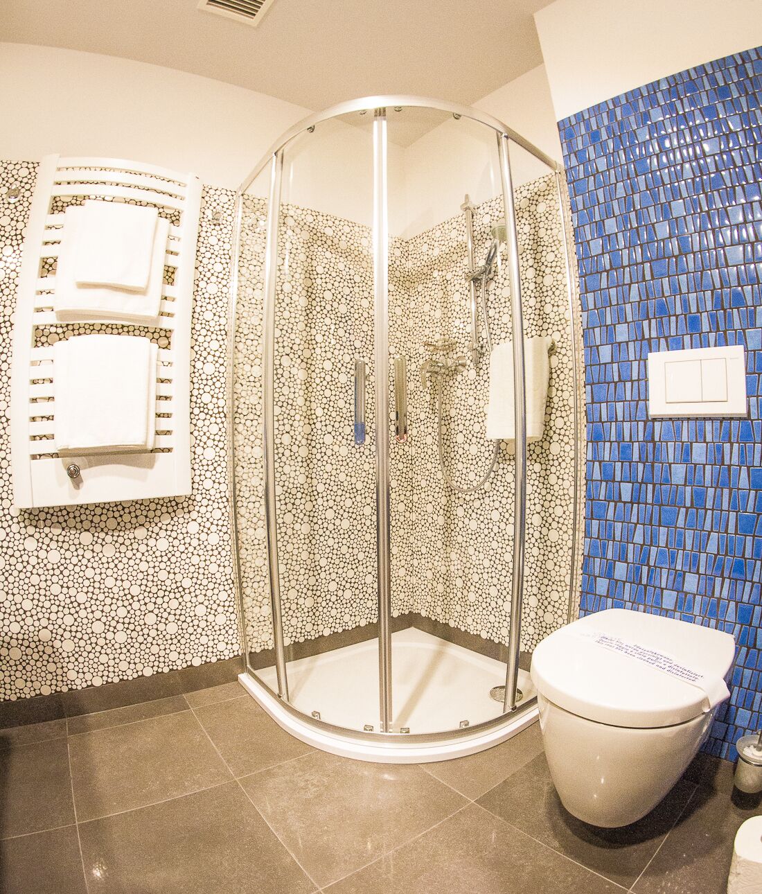 A bathroom with a glass-enclosed shower, a toilet, and a sink.