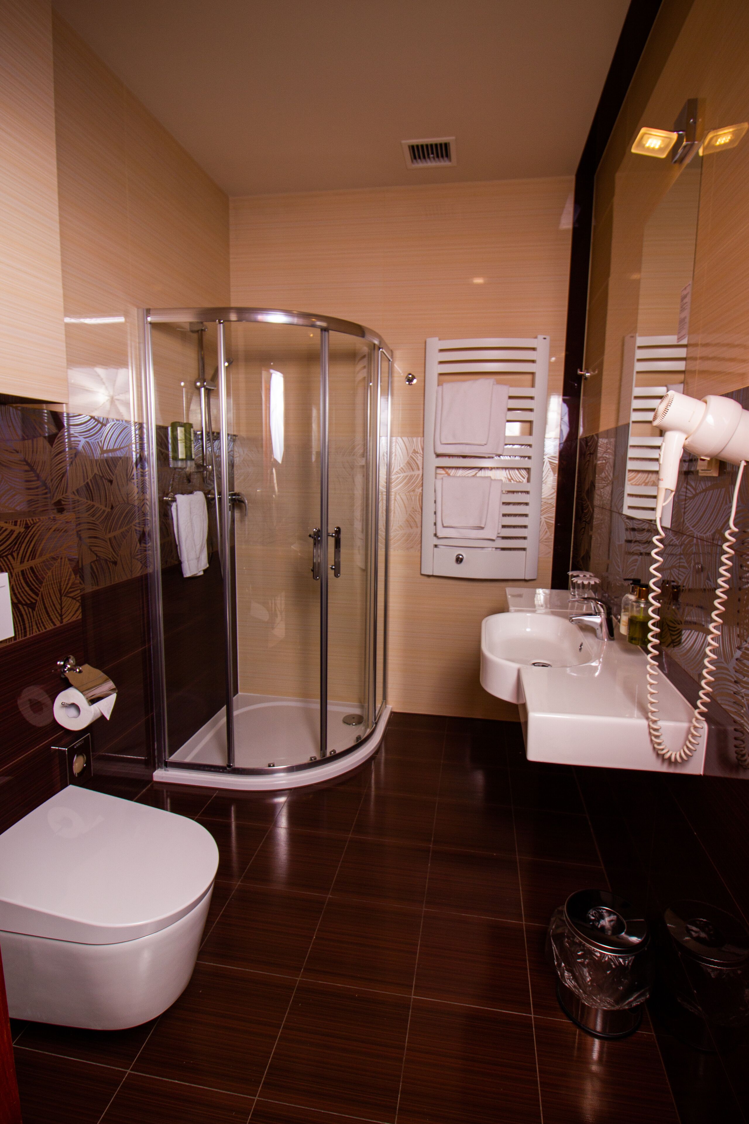 Un baño moderno con ducha de vidrio, inodoro blanco, lavamanos y secador de pelo.