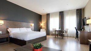 A modern hotel room with a large bed, bedside tables, a desk, a chair, and a TV. - Imperia Hotel & Suites Terrebonne (Terrebonne)