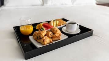 Un plateau avec des pâtisseries, un verre de jus d’orange et une tasse de café sur un lit.