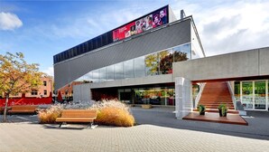 A modern building with a large digital billboard, a staircase, and outdoor seating. - Imperia Hotel & Suites Terrebonne (Terrebonne)