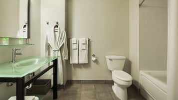 A modern bathroom with a glass sink, a white toilet, and a bathtub.
