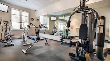 A gym with various exercise equipment, including treadmills, weight machines, and dumbbells.