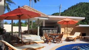 Zona de piscina amb gandules i ombrel·les, una piscina amb rajoles i vistes a un paisatge de muntanya.