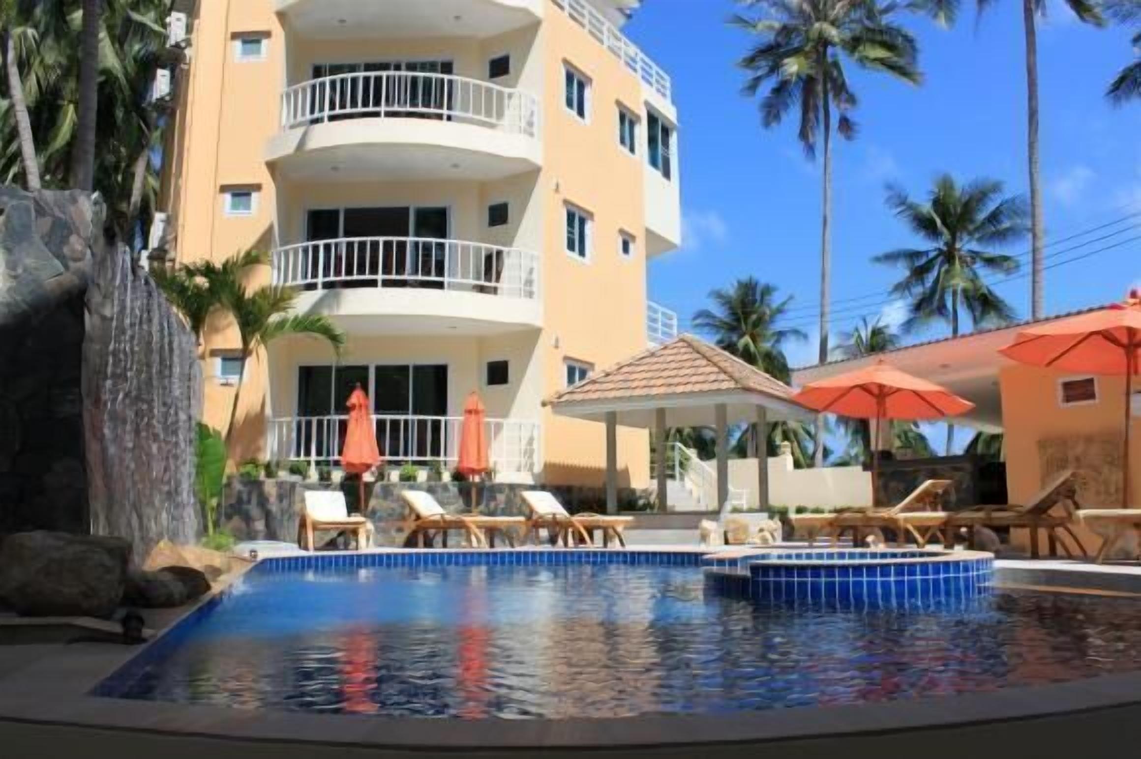 Un hôtel doté d’une piscine, de chaises longues et de palmiers.