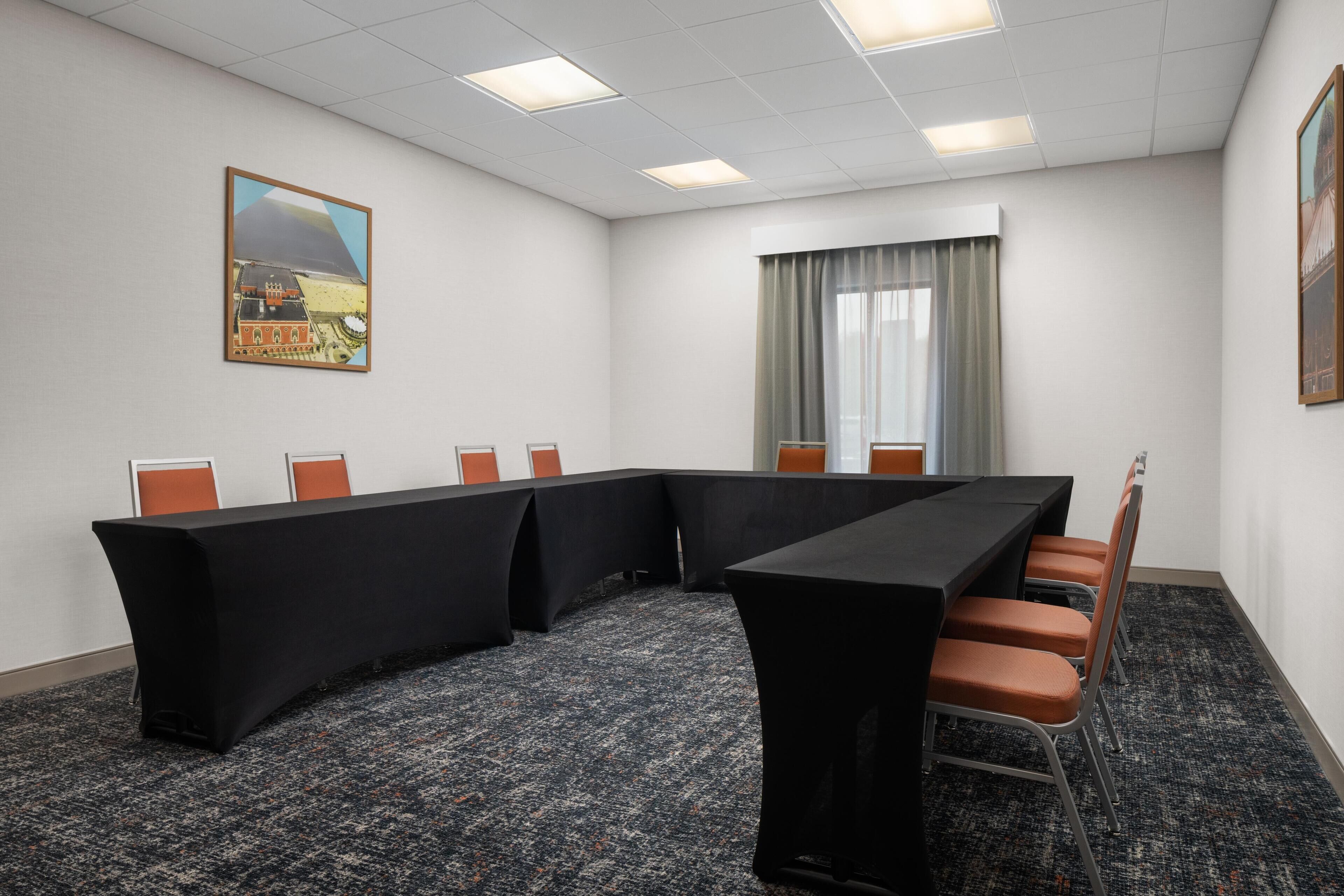 A conference room with a long table, chairs, and a carpeted floor.