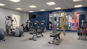 A gym with treadmills, weight machines, and a mirror.