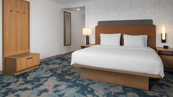 Ein Hotelzimmer mit einem großen Bett, einem Holzschrank, Nachttischen mit Lampen und einem gemusterten Teppich.
