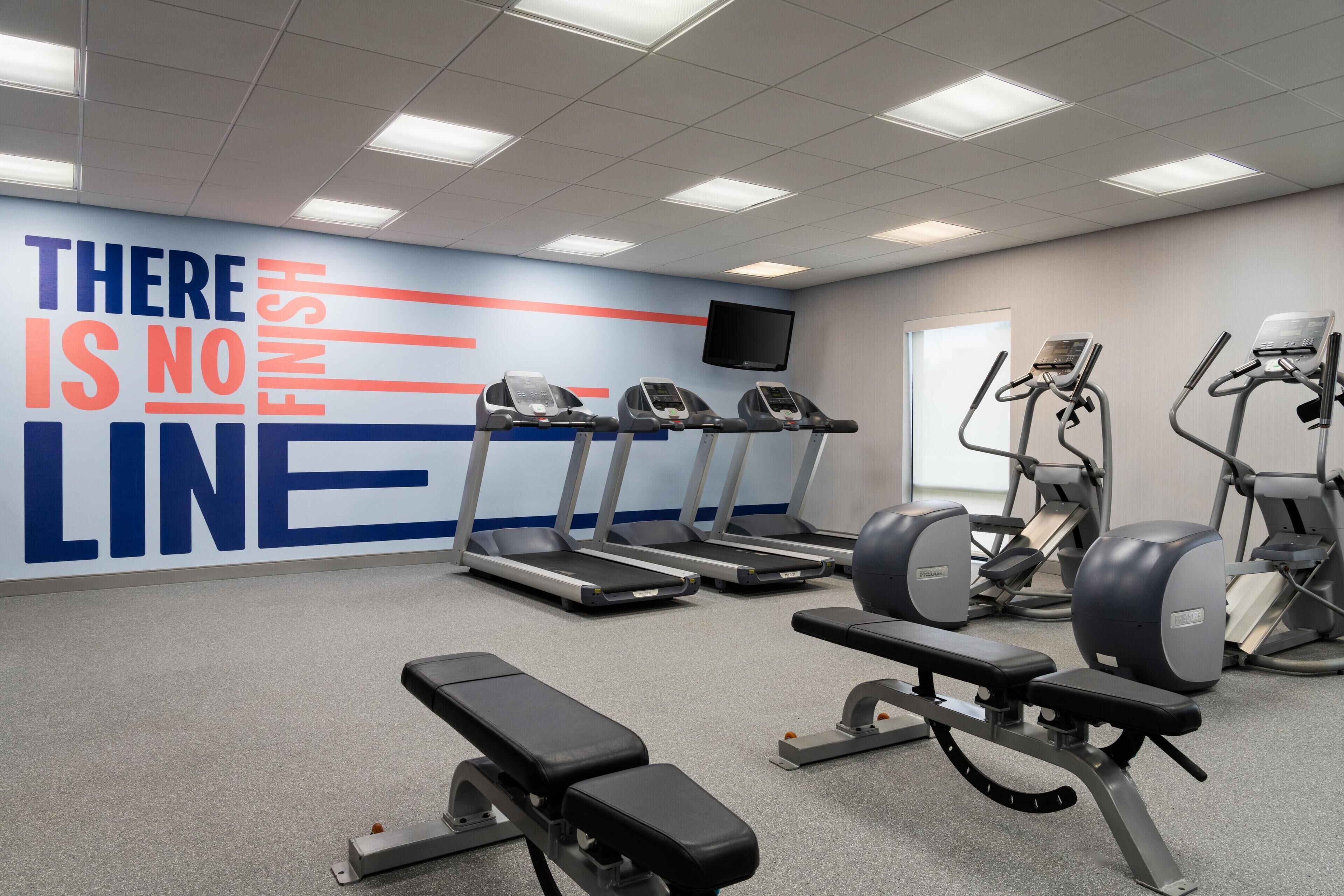 A gym with treadmills, weight machines, and a motivational wall.