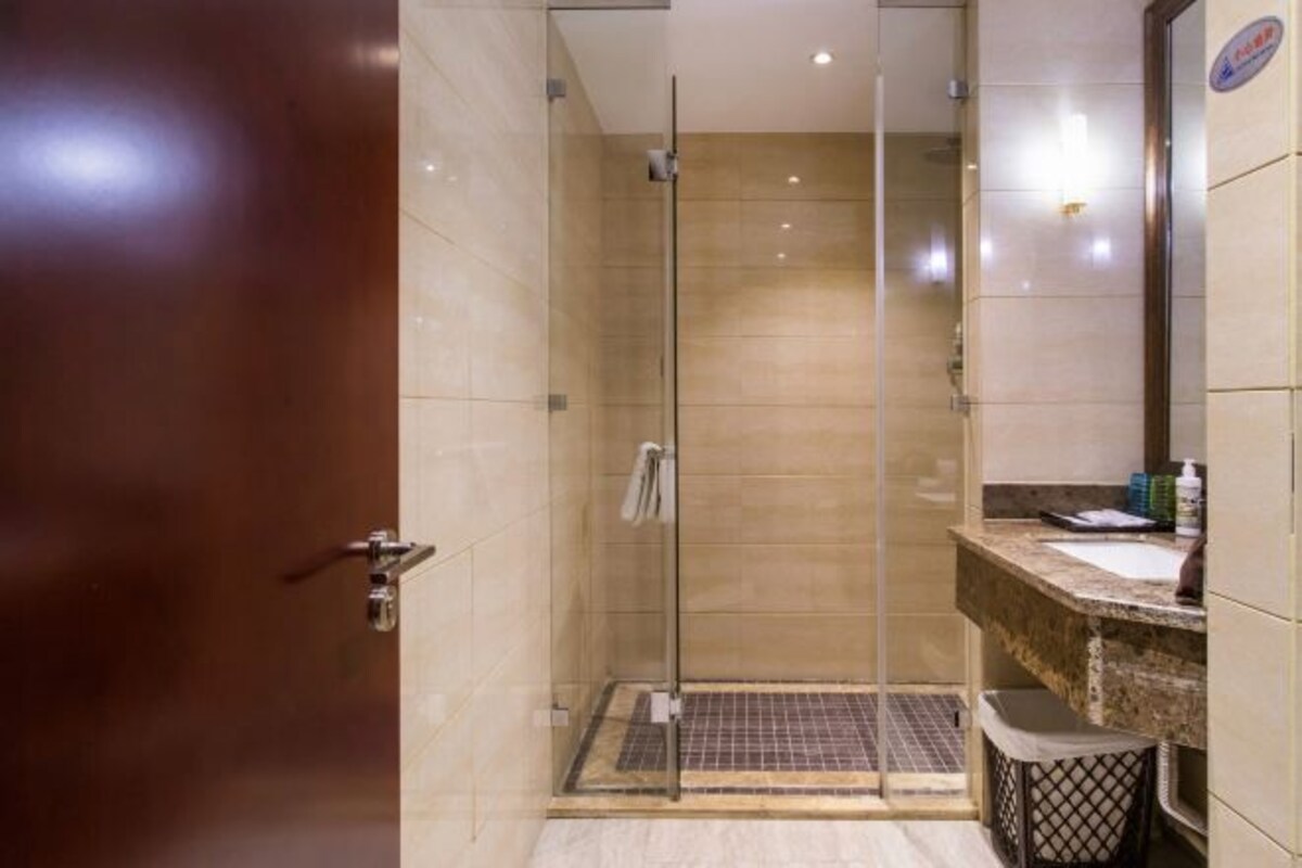 A modern bathroom with a glass-enclosed shower, a marble-tiled floor, and a sink with a countertop.