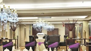 Un salón de banquetes con mesas redondas, fundas moradas para las sillas y un arreglo floral central.